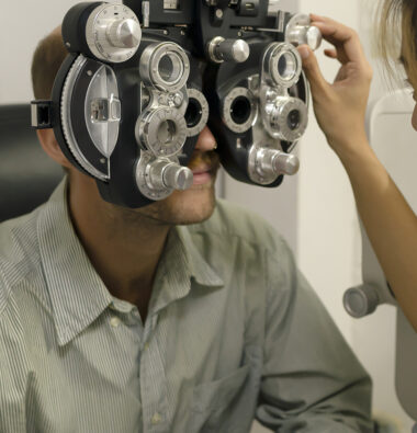 Asian female ophthalmologist examining caucasian men's eyes with special equipment, eye care specialist, eye health.