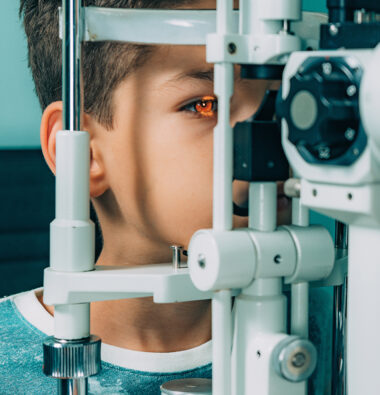 Ophthalmologist examining boy with slit lamp