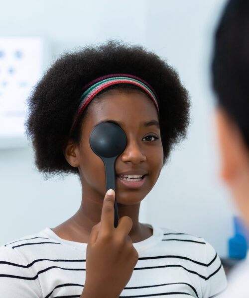 Young woman african american using occluder for eye test ophthalmological in optics clinic. woman checkup eye health with equipment opthalmology medical in hospital.
